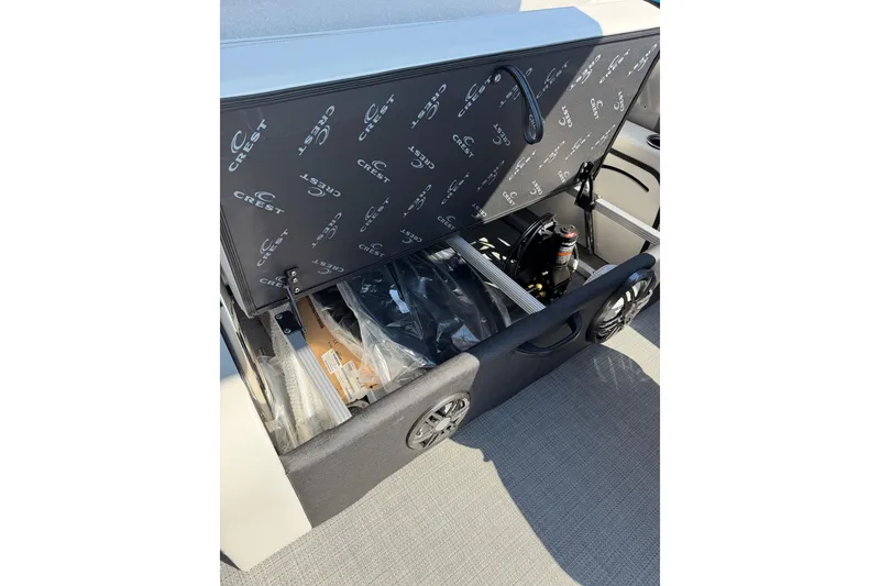 Slide: The Image of Storage compartment of 2026 Crest Conquest 250 SLSC boat, featuring organized interior and branded cover. - 32