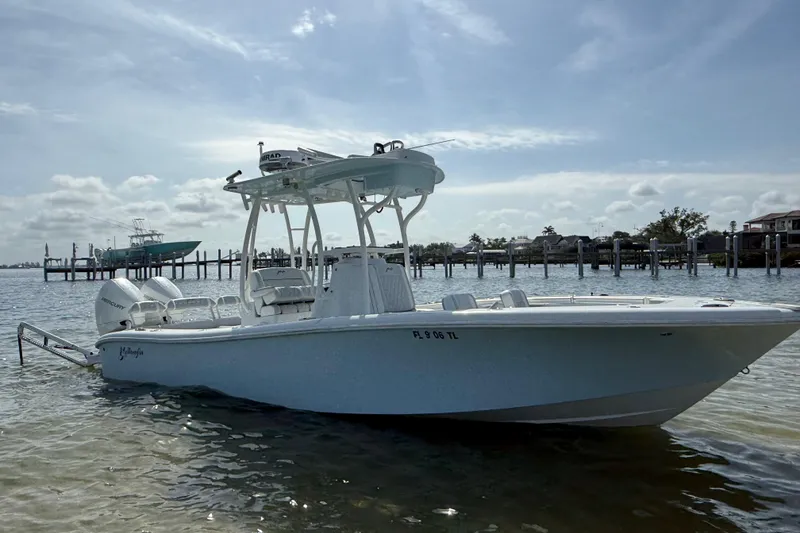 Slide: The Image of 2023 Yellowfin 26 Hybrid boat docked in calm waters under a cloudy sky. - 12