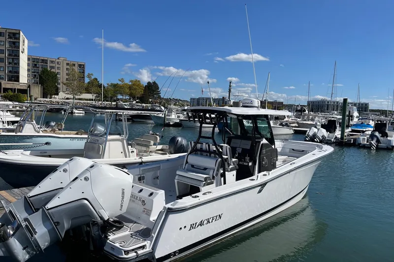 Slide: The Image of 2023 Blackfin 302 CC boat docked in a marina under a clear blue sky. - 2