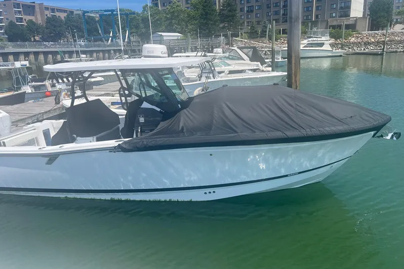 Slide: The Image of 2023 Blackfin 302 CC boat docked with cover, in a marina setting. - 27