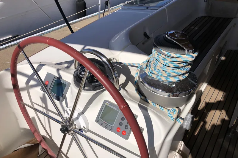 Slide: The Image of Steering wheel and controls of a 2001 Beneteau 50 yacht, featuring navigation instruments and winch. - 20
