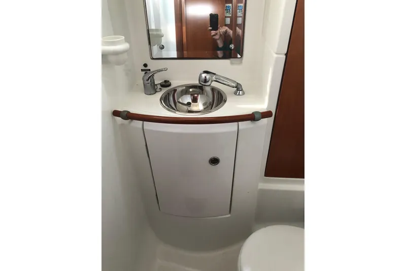 Slide: The Image of Bathroom sink area in a 2001 Beneteau 50 yacht, featuring a mirror and faucet. - 7