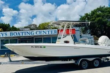 The Image of 2017 Boston Whaler 240 Outrage boat on trailer at boating center, under blue sky. - 1