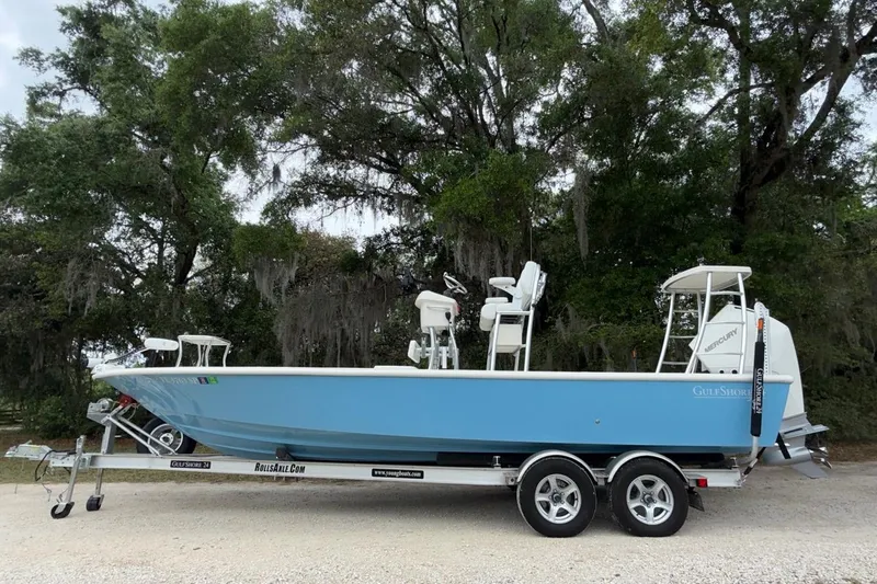 Slide: The Image of 2021 Young Boats Gulf Shores 24 on trailer, parked near lush trees. - 3