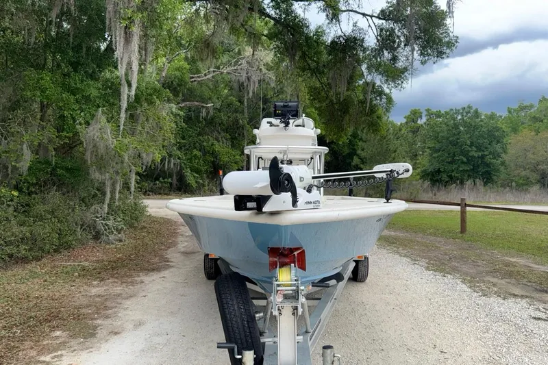 Slide: The Image of 2021 Young Boats Gulf Shores 24 on trailer, surrounded by lush greenery. - 5
