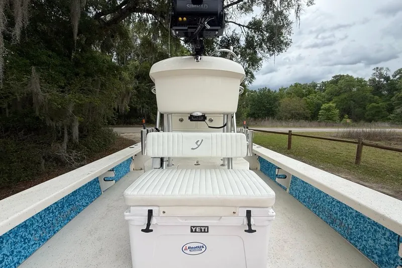 Slide: The Image of 2021 Young Boats Gulf Shores 24 with white seating and Yeti cooler, parked outdoors. - 7
