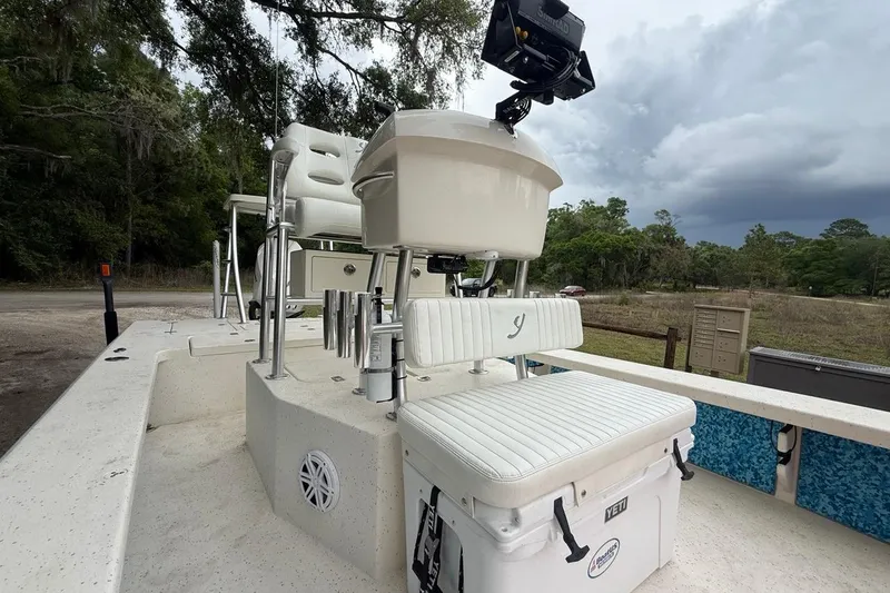 Slide: The Image of 2021 Young Boats Gulf Shores 24 interior with seating and equipment, set against a wooded backdrop. - 8