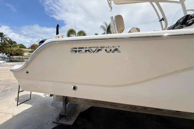 Slide: The Image of 2016 Sea Fox 226 Commander boat side view with logo, parked outdoors. - 6