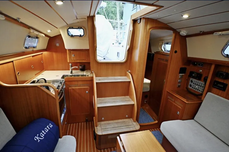 Slide: The Image of Interior of a 2020 Hallberg Rassy 310 sailboat, featuring a cozy wooden cabin design. - 2