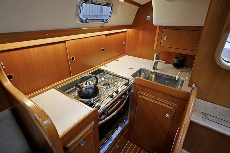 Slide: The Image of Interior of 2020 Hallberg Rassy 310 yacht kitchen with stove, sink, and wooden cabinetry. - 9