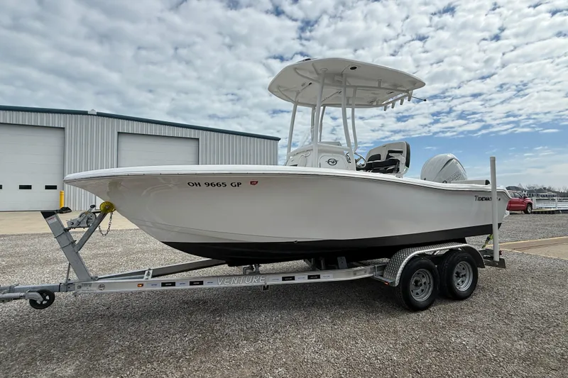 The Image of 2025 Tidewater 198 CC Adventure boat on trailer, parked near a warehouse under a cloudy sky. - 0