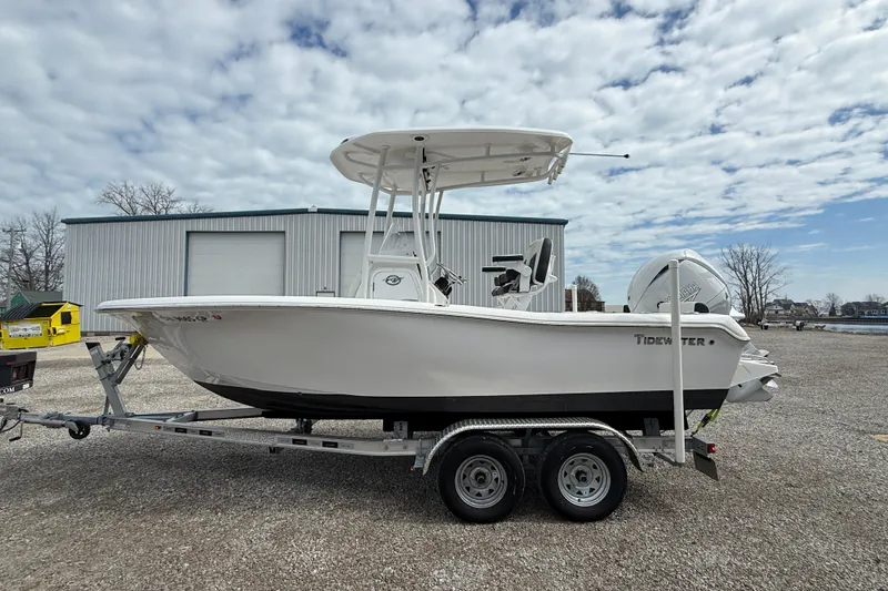 Slide: The Image of 2025 Tidewater 198 CC Adventure boat on trailer, parked outdoors under cloudy sky. - 22
