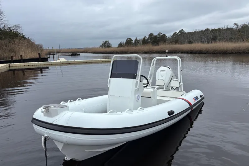 Slide: The Image of 2026 Airrib 18 inflatable boat docked on a calm river under cloudy skies. - 7