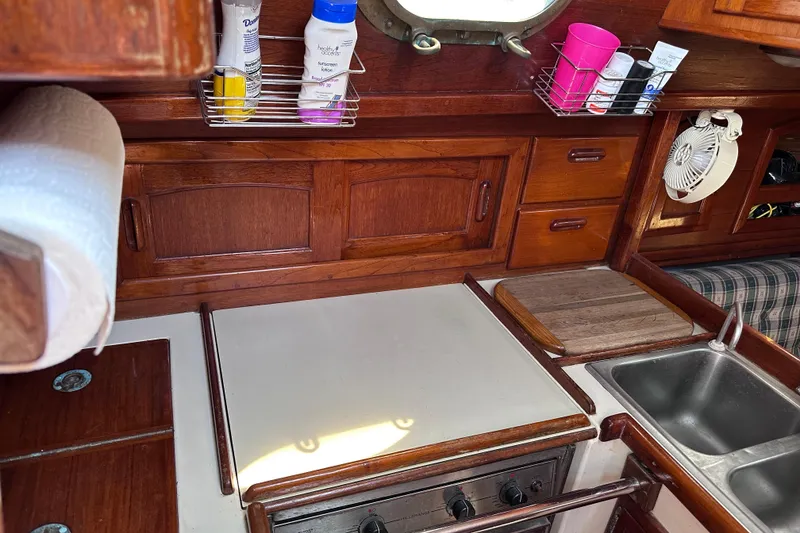 Slide: The Image of 1986 Pacific Seacraft 34 yacht galley with wooden cabinetry, stove, and sink. - 27
