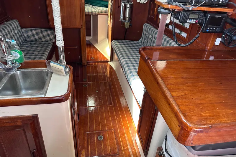 Slide: The Image of 1986 Pacific Seacraft 34 interior with wood finish, sink, and plaid seating. - 31