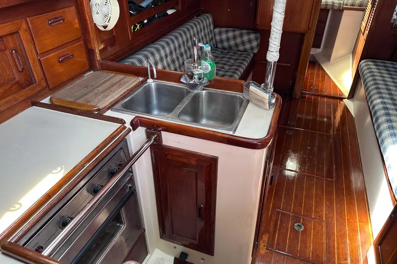 Slide: The Image of Interior of a 1986 Pacific Seacraft 34 sailboat, featuring a compact kitchen and seating area. - 32