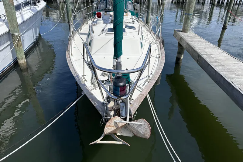 Slide: The Image of 1986 Pacific Seacraft 34 sailboat docked at marina, featuring anchor and green sail cover. - 4