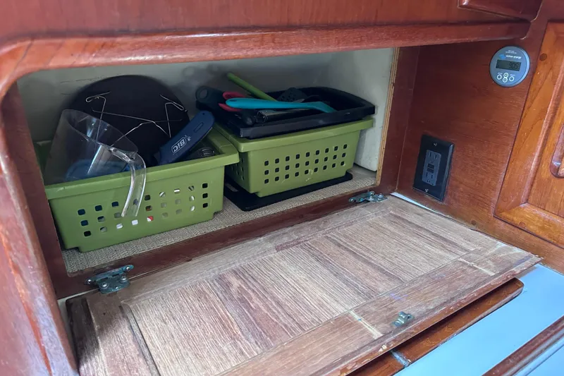 Slide: The Image of Storage compartment in a 1986 Pacific Seacraft 34 sailboat with organized green baskets. - 44