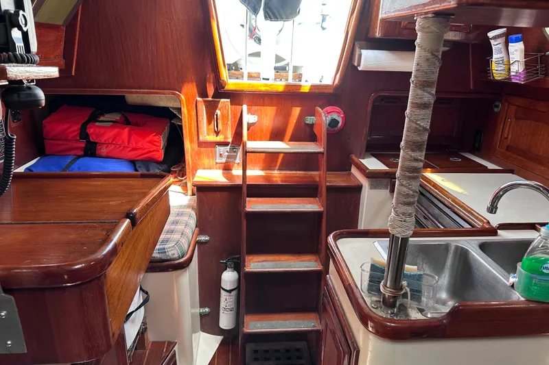Slide: The Image of Interior of 1986 Pacific Seacraft 34 sailboat with wooden cabinetry and compact kitchen area. - 54