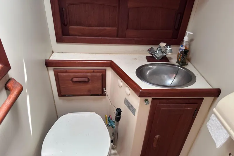 Slide: The Image of 1986 Pacific Seacraft 34 yacht bathroom with sink, toilet, and wooden cabinetry. - 57