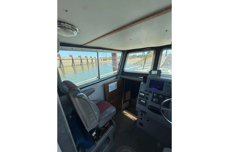 Slide: The Image of Interior of 2004 Norsco 28 boat, featuring helm and navigation equipment with waterfront view. - 13