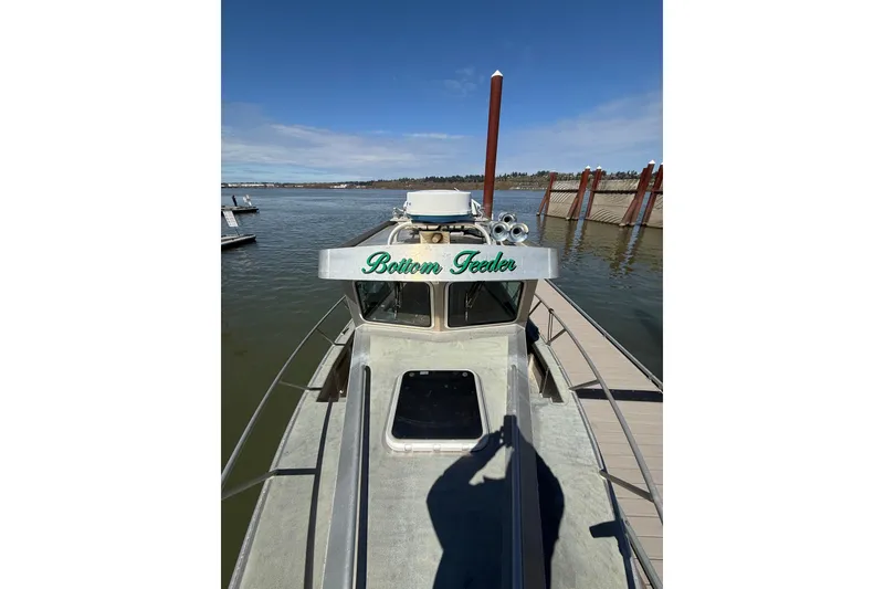 Slide: The Image of 2004 Norsco 28 boat named "Bottom Feeder" docked at a marina under clear skies. - 23
