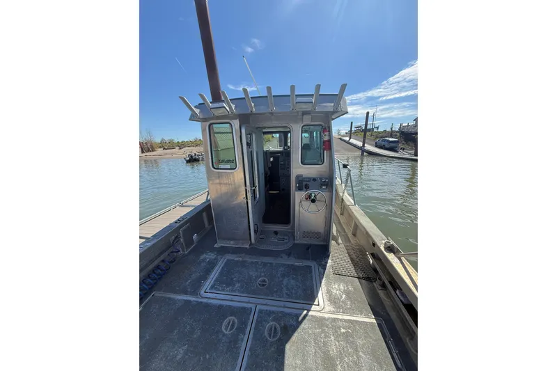 Slide: The Image of 2004 Norsco 28 boat docked by a calm waterfront under a clear blue sky. - 7