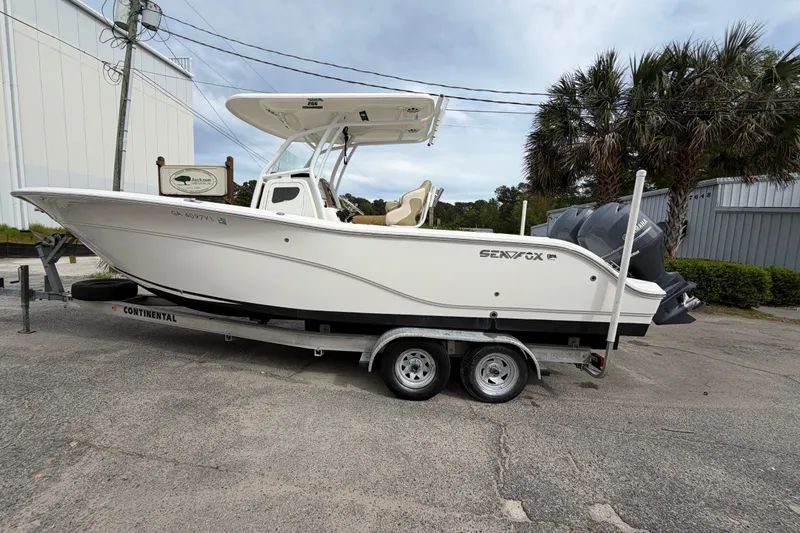 Slide: The Image of 2015 Sea Fox 266 Commander boat on trailer, parked outdoors near palm trees. - 3