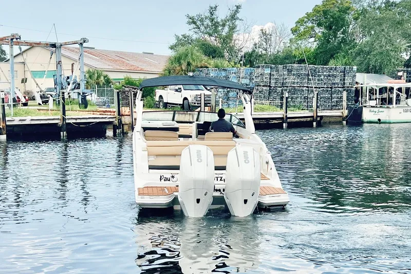 Slide: The Image of 2019 Sea Ray SDX 290 Outboard cruising on a calm waterway near a dock. - 6