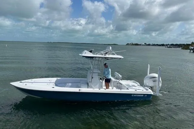 The Image of 2025 Contender 26 Bay boat on water, person standing, cloudy sky background. - 0