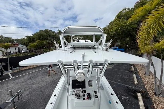 Slide: The Image of 2025 Contender 26 Bay boat with advanced navigation equipment, docked near tropical foliage. - 11