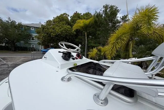 Slide: The Image of 2025 Contender 26 Bay boat helm with steering wheel and controls, surrounded by tropical foliage. - 12