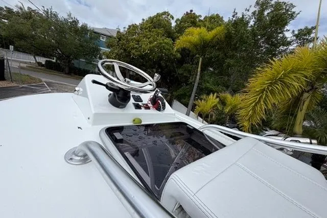 Slide: The Image of 2025 Contender 26 Bay boat helm with steering wheel and lush greenery background. - 14