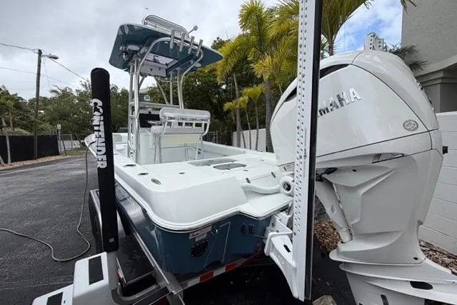 Slide: The Image of 2025 Contender 26 Bay boat with Yamaha engine, parked on a trailer near palm trees. - 26