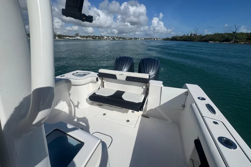 Slide: The Image of 2023 Tidewater 292 CC Adventure boat on calm water, featuring dual engines and seating. - 18