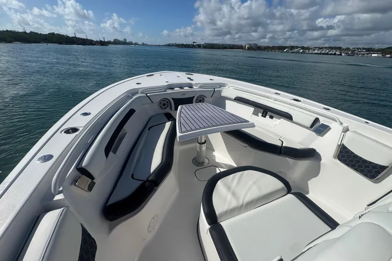 Slide: The Image of 2023 Tidewater 292 CC Adventure boat interior with seating and table on calm water. - 19