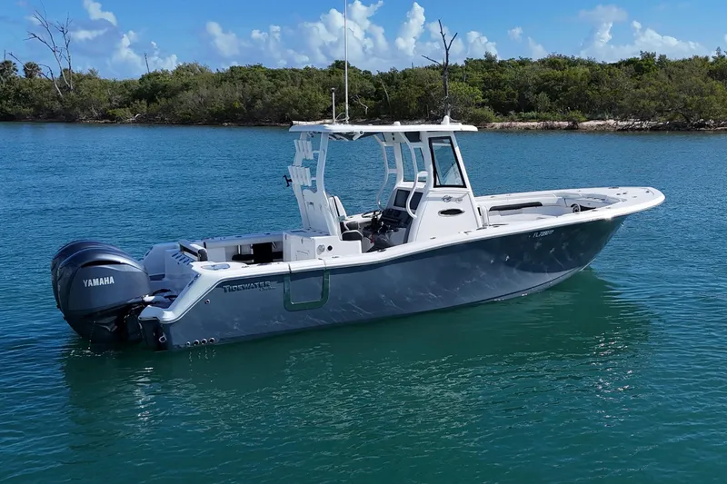 Slide: The Image of 2023 Tidewater 292 CC Adventure boat on calm blue water with Yamaha engine. - 2
