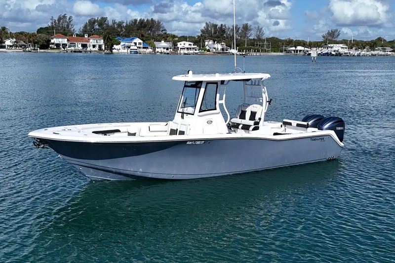 Slide: The Image of 2023 Tidewater 292 CC Adventure boat on calm water, coastal homes in background. - 4
