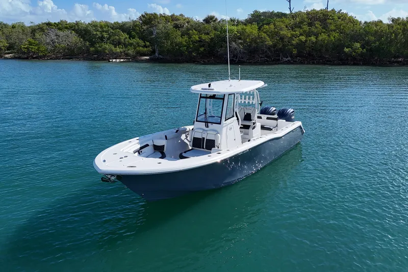 Slide: The Image of 2023 Tidewater 292 CC Adventure boat on calm water, surrounded by lush greenery. - 5