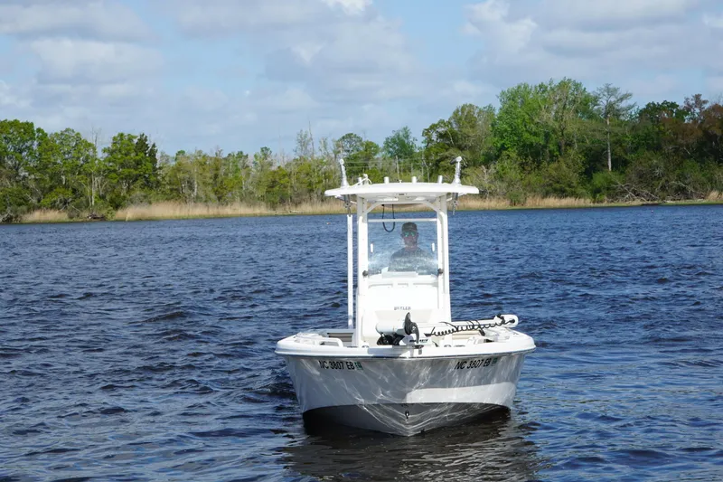 Slide: The Image of 2015 Everglades 243 Center Console boat on a scenic lake with lush greenery. - 2