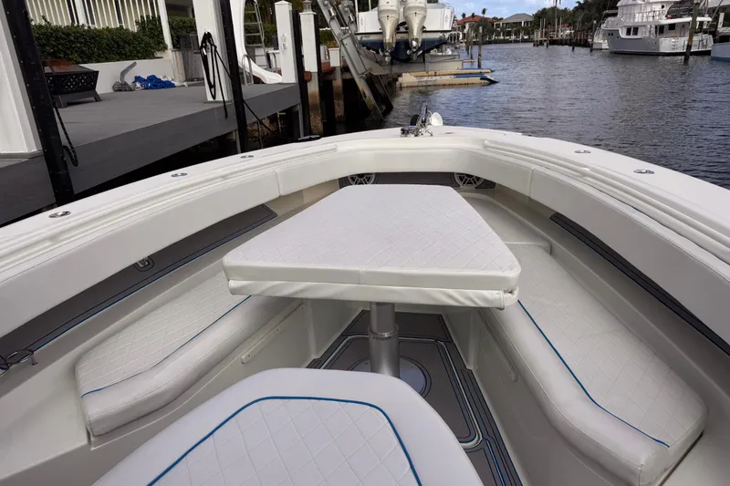 Slide: The Image of 2016 Hydra-Sports 4200 Siesta boat interior with cushioned seating and table, docked by the water. - 11