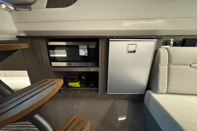 Slide: The Image of 2025 Sea Ray SLX 400 interior with microwave, mini-fridge, and seating area. - 25