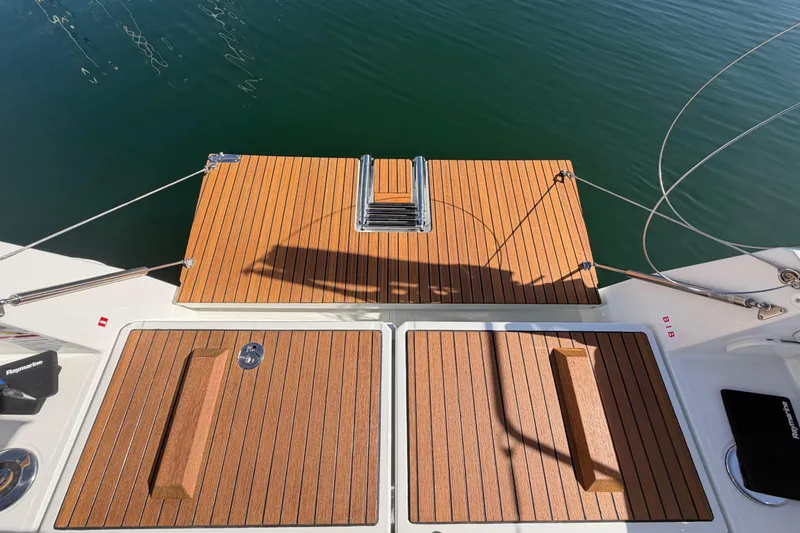 Slide: The Image of 2024 Jeanneau Sun Odyssey 349 teak deck, featuring elegant wood finish and water backdrop. - 28