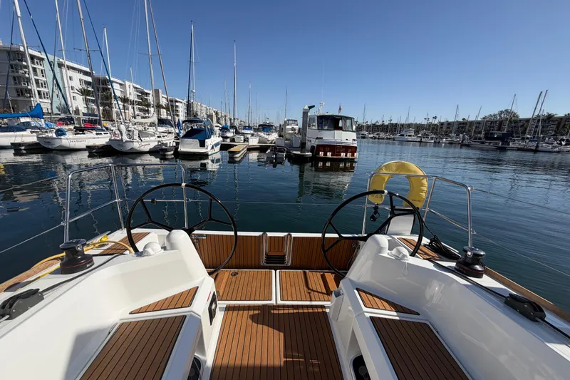 Slide: The Image of 2024 Jeanneau Sun Odyssey 349 sailboat docked in a marina, featuring dual steering wheels. - 32