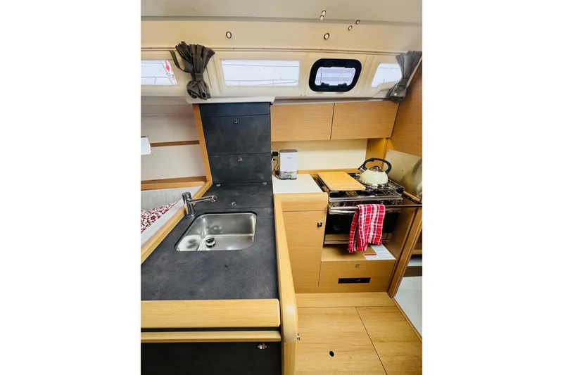Slide: The Image of 2024 Jeanneau Sun Odyssey 349 interior kitchen with sink, stove, and wooden cabinetry. - 45