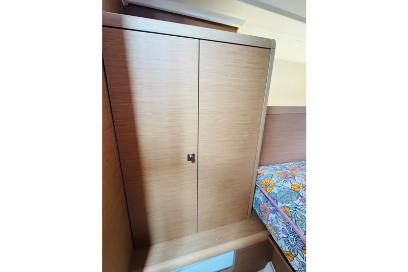 Slide: The Image of 2024 Jeanneau Sun Odyssey 349 interior with wooden cabinet and floral-patterned bedding. - 62
