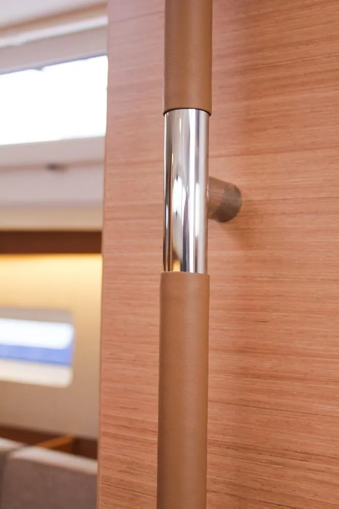 Slide: The Image of Interior detail of 2025 Jeanneau Sun Odyssey 440 yacht, featuring a sleek wooden and metal handrail. - 29