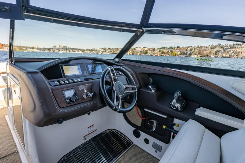 Slide: The Image of 2019 Cobalt R30 boat cockpit with steering wheel and navigation controls on a scenic lake. - 10
