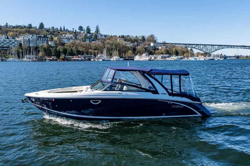 Slide: The Image of 2019 Cobalt R30 boat cruising on a scenic lake with cityscape and bridge in background. - 25