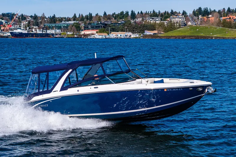 Slide: The Image of 2019 Cobalt R30 boat cruising on a scenic lake with cityscape background. - 27